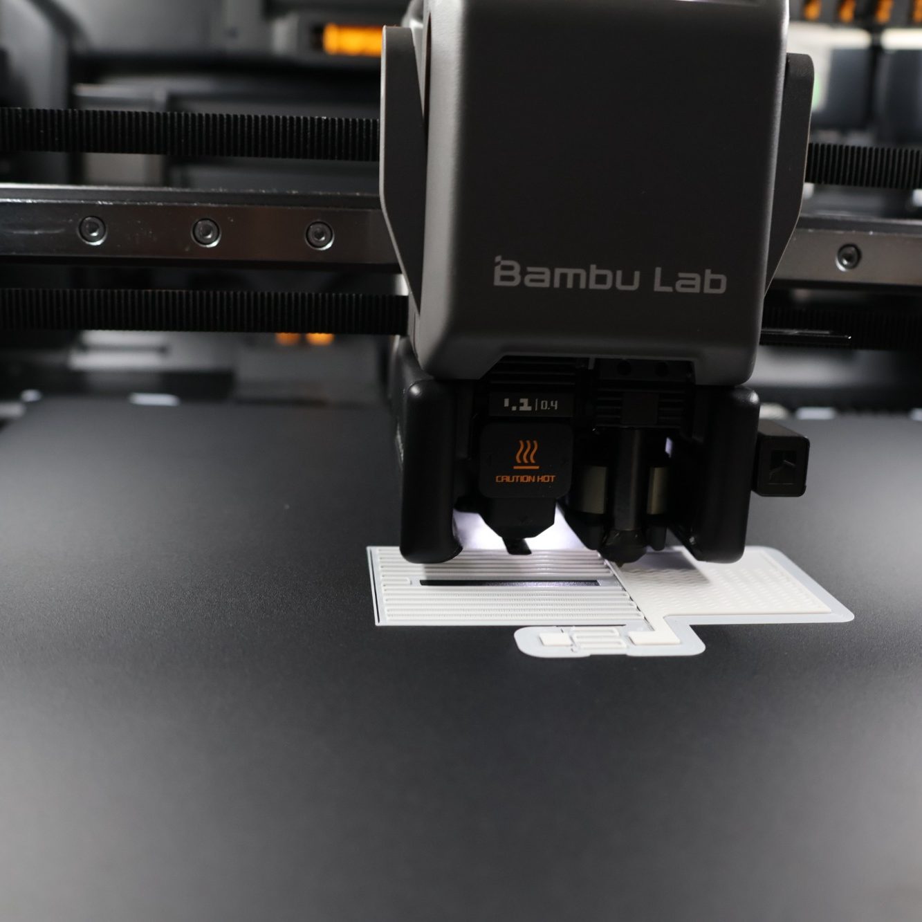 H2C Druckt PLA Teil 3D-Drucker von Bambu Lab, der gerade ein Objekt auf einer Druckoberfläche erstellt.