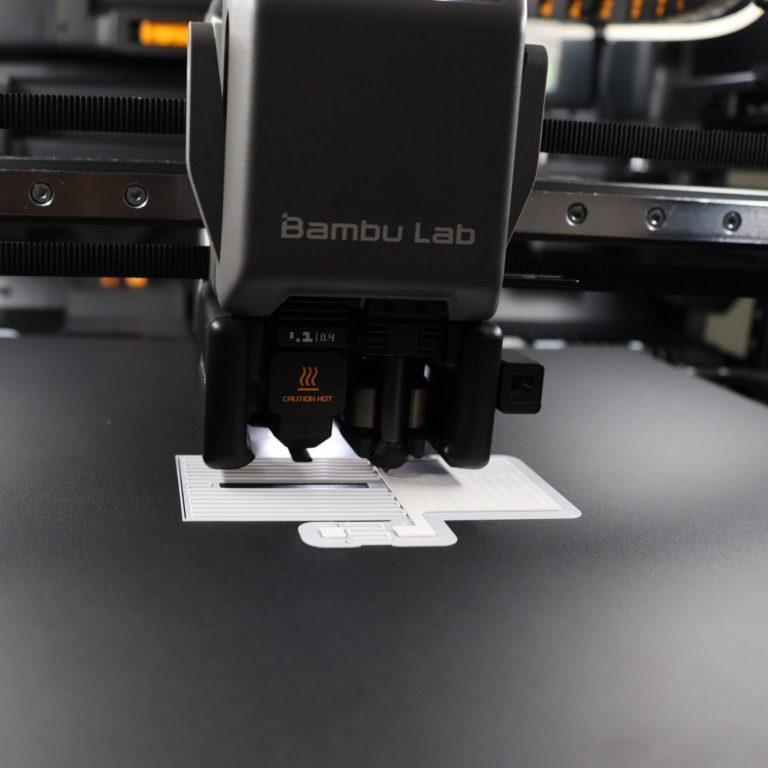 3D Drucker 3D-Drucker von Bambu Lab, der gerade ein Objekt auf einer schwarzen Druckoberfläche erstellt.